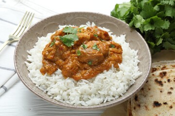 Delicious chicken tikka masala with rice, cilantro and lavash on white wooden table, closeup