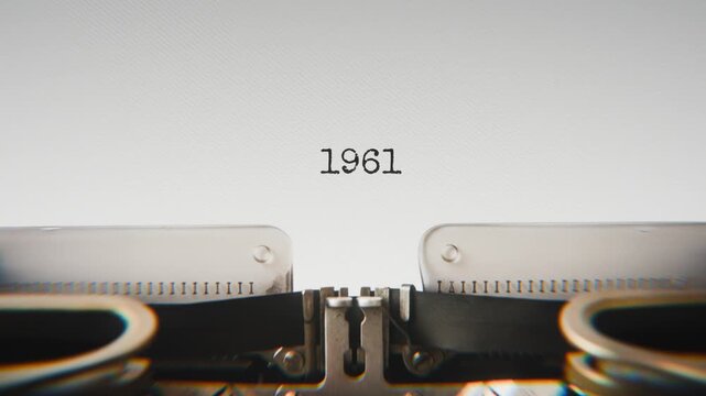 Old mechanical typewriter typing Year 1961 in a close-up view, with metal letters striking the white paper.
