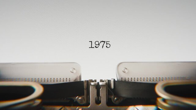 Old mechanical typewriter typing Year 1975 in a close-up view, with metal letters striking the white paper.