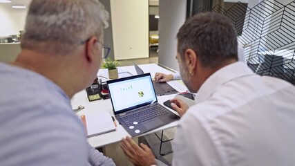 Three business colleagues actively engage in a productive office meeting, analyzing important financial data and strategic plans displayed on a laptop screen. - Powered by Adobe