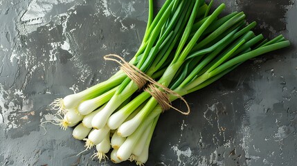 Vibrant green onions freshly harvested, neatly bundled with twine and displayed on a rustic dark textured surface, ready for cooking
