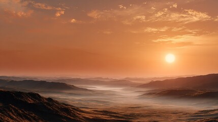 Stunning vast mountain range landscape shrouded in low lying mist during  bright orange sunset