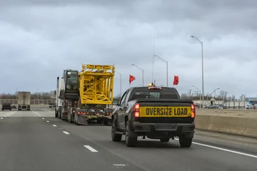 Canvas schilderij Voertuigen Truck carrying an oversized load is being escorted by safety vehicle on busy American highway  © ungvar