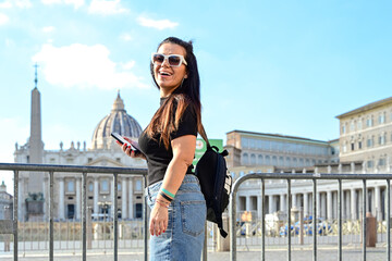Fototapeta premium Rome,Italy, Vatican City, Rome, Saint Peter's Basilica in St. Peter's Square Young beautiful woman using a mobile phone taking a pictures.Concept of Italian gastronomy and travel