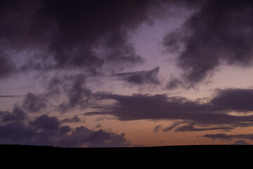 Purple and pale golden sky with grey clouds at daybreak just before sunrise on a January morning over clifftops at Flamborough Headland, East Yorkshire, England, UK