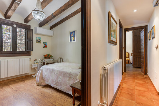 Rustic bedroom and hallway with wood beams, framed art, and terracotta tile flooring