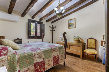 Elegant rustic bedroom with wooden beams, vintage furniture, and floral patchwork bedding