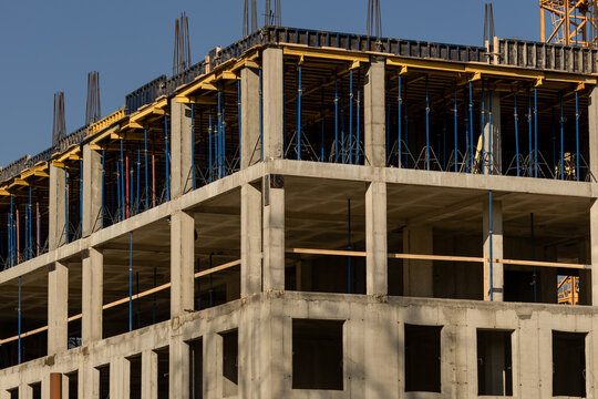 construction site with crane and building in background. yellow colored crane is in center of stage. construction of multi-storey building. monolithic technology. urbanization.