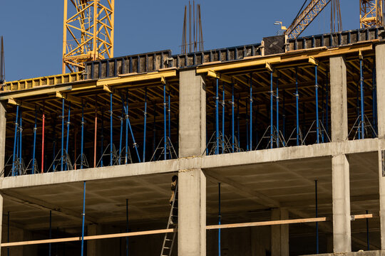 construction site with crane and building in background. yellow colored crane is in center of stage. construction of multi-storey building. monolithic technology. urbanization. - Powered by Adobe