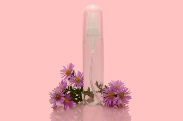 A transparent container with purple flowers on a pink background. A bottle for liquid.