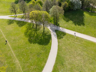 Aerial view from the drone of a man walking and a cyclist in the green city park