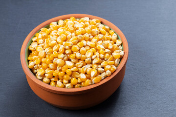 Bowl with popcorn kernels on a gray stone surface