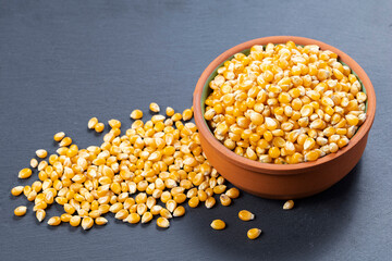 Bowl with popcorn kernels on a gray stone surface