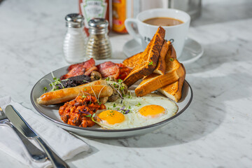 British breakfast with eggs, sausage, beans, tomatoes, toast, and blood pudding
