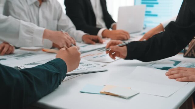 A diverse team of professionals engages in a collaborative meeting in a modern office. They use technology and documents to strategize and brainstorm innovative solutions. SACTR