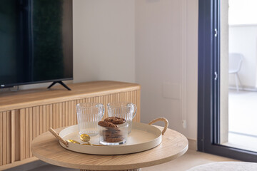 Glass mugs and cookies on wooden coffee table in cozy living room setting