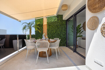 Sunny modern terrace with dining setup and sliding glass door to living room