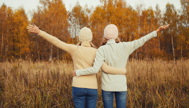 Happy young women friends having fun in autumn park, girlfriends walking together outdoors
