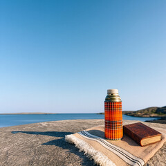 Vintage seaside excursion with thermos and blanket resting on rugged coastal cliffs