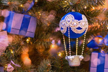 Blue balloon with basket decorates Christmas tree.