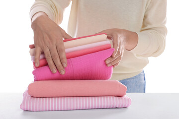 Woman with stack of clean clothes at table on white background, closeup