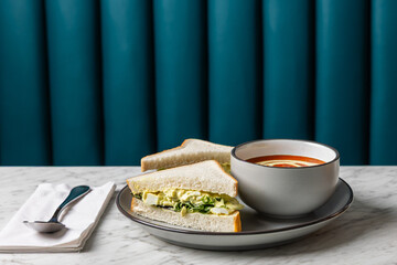 egg salad sandwich with tomato soup on marble table