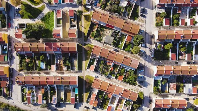 Aerial view of closely packed houses with orange rooftops, interspersed with green spaces and roads, creating a structured urban landscape, Lisbon, Lisbon, Portugal.