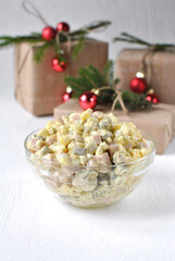 A festive bowl of creamy Olivier salad sits on a bright holiday table, with wrapped gifts, pine branches, and red ornaments creating a cozy Christmas atmosphere.