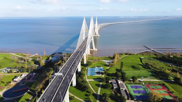 Aerial view of the Vasco da Gama Bridge stretching across the Tagus River, casting a long shadow on the calm waters, Lisbon, Lisbon, Portugal.