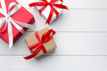 Beautiful gift boxes on white wooden background, flat lay. Space for text