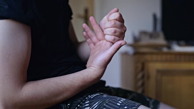 A man stretches his fingers and cracks his knuckles in a detailed close-up. This routine action provides joint comfort and stress relief, promoting hand flexibility and relaxation through self-care.