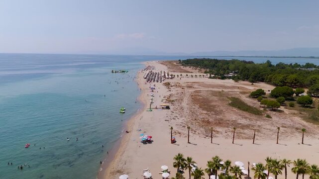 Low altitude aerial tracking shot along the pristine white sands of Keramoti Blue Flag Beach, Kavala, Greece, highlighting the turquoise Thracian Sea and coastal pine forests.
