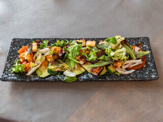 Gourmet Octopus and Mixed Green Salad on a Rectangular Slate Plate
