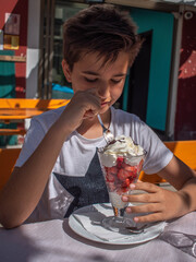 Boy Enjoying a Strawberry and Whipped Cream Sundae Outdoors