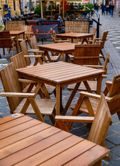Outdoor cafe with empty wooden tables and chairs on the patio. Inviting relaxation and leisurely moments.