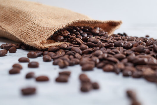 Roasted Jamaican Blue Mountain coffee beans coming out of a brown burlap pouch
