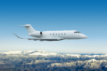White luxury bizjet flies over snow covered mountain ranges