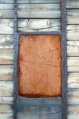Old wooden wall with framed metal panel and vertical beams.
