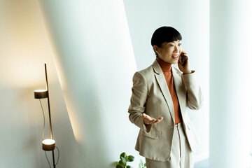 Businesswoman in elegant suit engaged in phone conversation in modern office setting