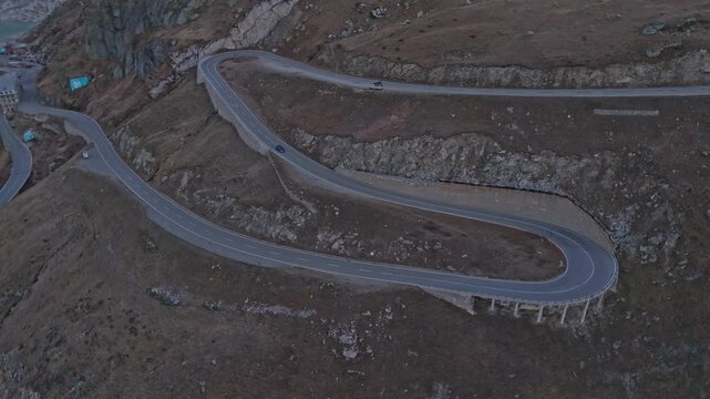 Drone shot of Furka Pass, scenic curves in the Swiss Alps at sunrise.