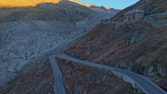 Aerial view of winding Furka Pass with traffic at dawn, Swiss Alps.