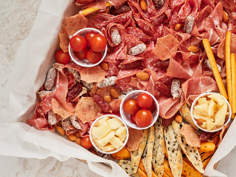 A beautifully arranged charcuterie board showcases various cured meats, cheeses, almonds, and cherry tomatoes. Perfect for gatherings or casual snacking, this spread invites sharing and enjoyment
