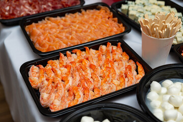 Assorted seafood and cheese platter display. A beautifully arranged platter showcasing an assortment of seafood including shrimp and salmon, paired with cubes of cheese and wooden utensils.