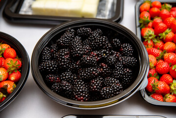 Fresh berries variety in black bowl. A selection of fresh berries, including blackberries and strawberries, displayed in a black bowl.