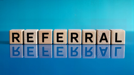 Referral concept displayed with wooden blocks on a blue reflective surface showcasing business strategy marketing and wordofmouth advertising for growth and customer acquisition success