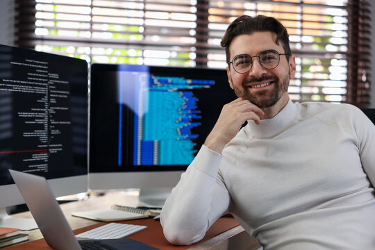 Fototapeta Portrait of smiling programmer in glasses at workplace