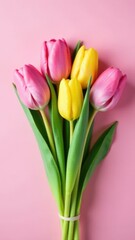 Fototapeta premium A bouquet of pink and yellow tulips against a pink background