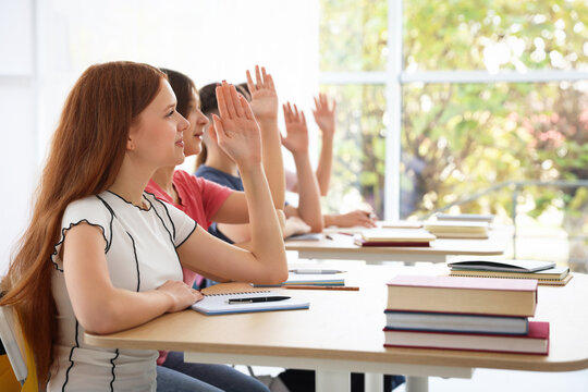 Students raising hands during lesson in classroom