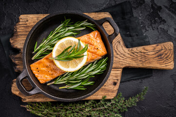 Fried salmon fillet with herbs, grilled fish steak in a pan. black background. top view