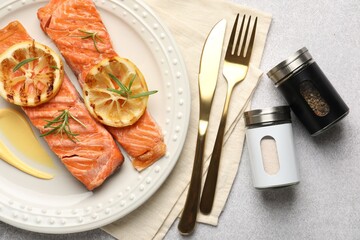 Salt pepper shakers and grilled salmon served on light table, flat lay